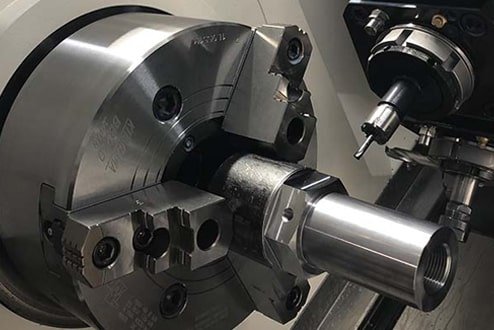 A CNC lathe machining a metal part during high-volume production.