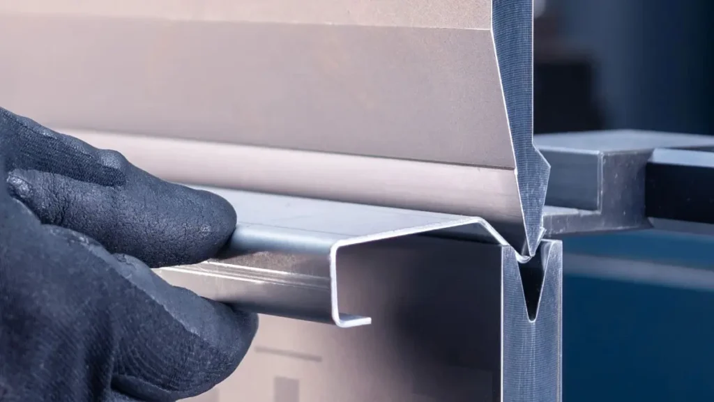 Worker's gloved hand bending a steel sheet.