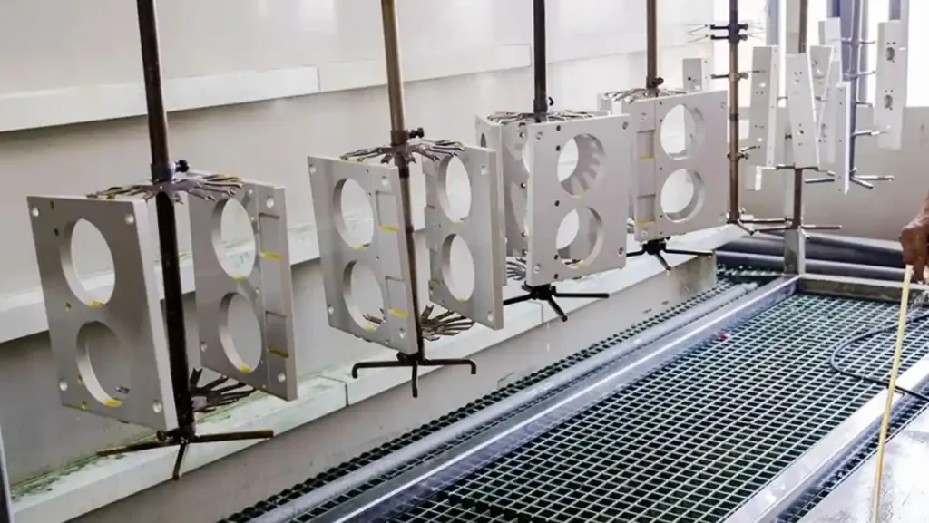 Metal parts hanging in an anodizing bath.