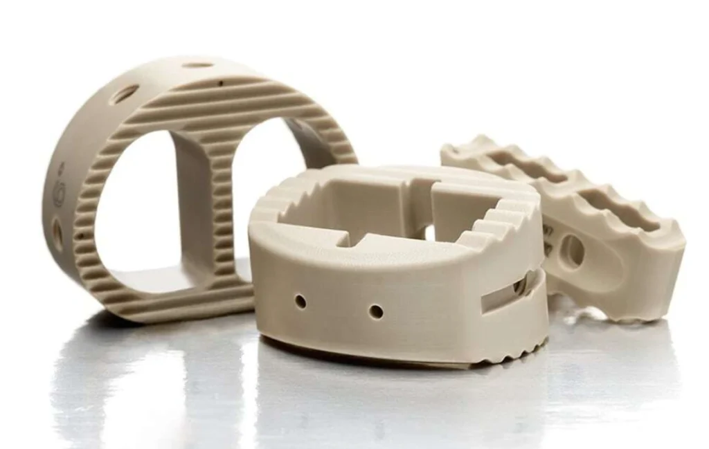 Three CNC-machined PEEK parts with holes and textured surfaces.