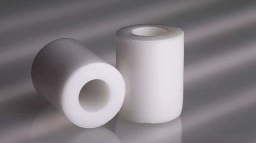 Two short, white, round CNC machined ceramic parts with hollow centers