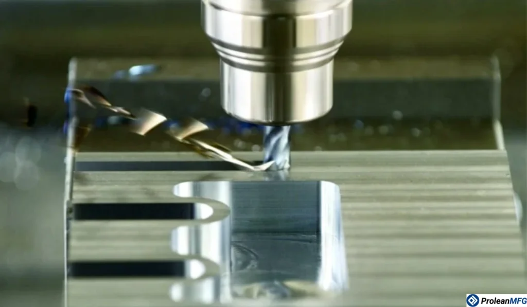 Close-up of a small metal block being machined by a fast-rotating CNC mill with metal chips flying out