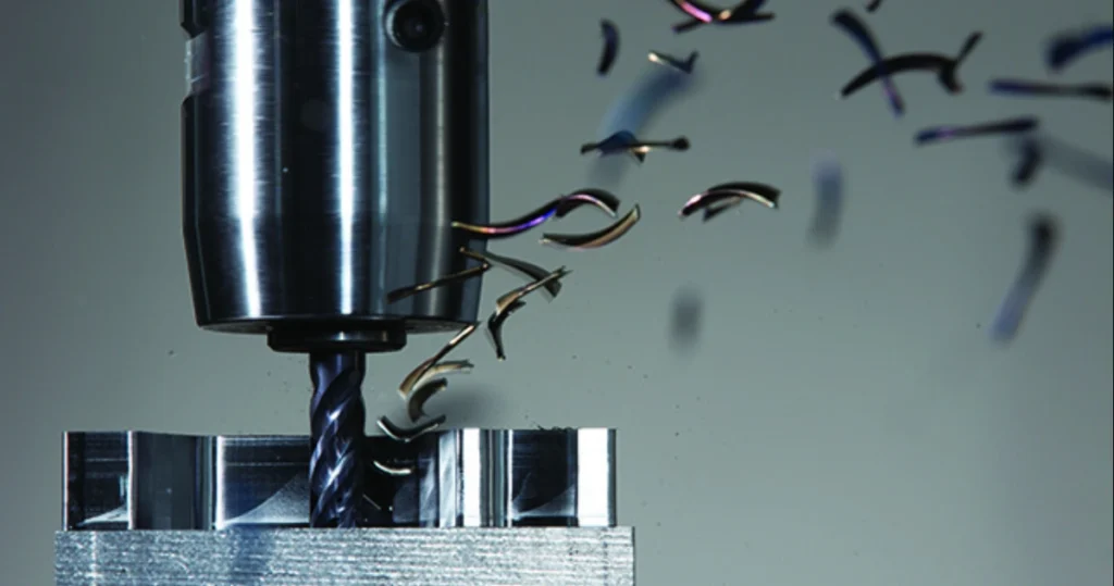CNC milling process showing large side grooves on a metal workpiece with metal chips flying away during cutting
