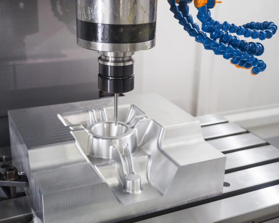 CNC milling of a white mold-making part featuring recessed and protruding profiles, with visible coolant nozzles