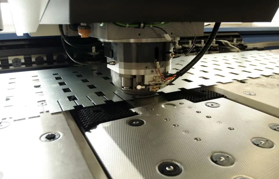 CNC punching machine with turret and die set, automatically punching holes and shapes into a metal sheet