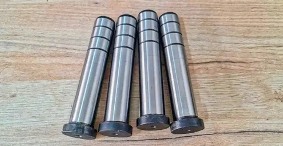 CNC turned carbon steel parts with cylindrical flat heads and elongated, narrower cylindrical ends, resembling oversized bolts