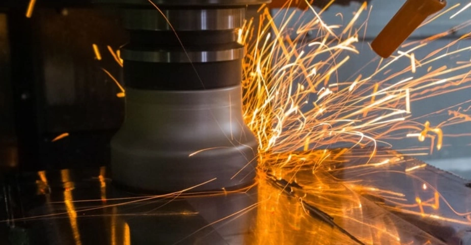 CNC milling machine cutting an Inconel workpiece with visible sparks flying from the cutting area.
