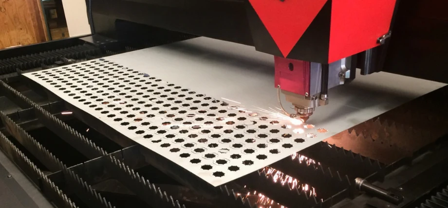 laser cutting machine working on a metal sheet, creating a pattern of circular holes