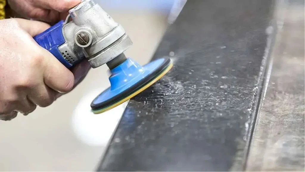 Handheld polisher smoothing a metal surface.