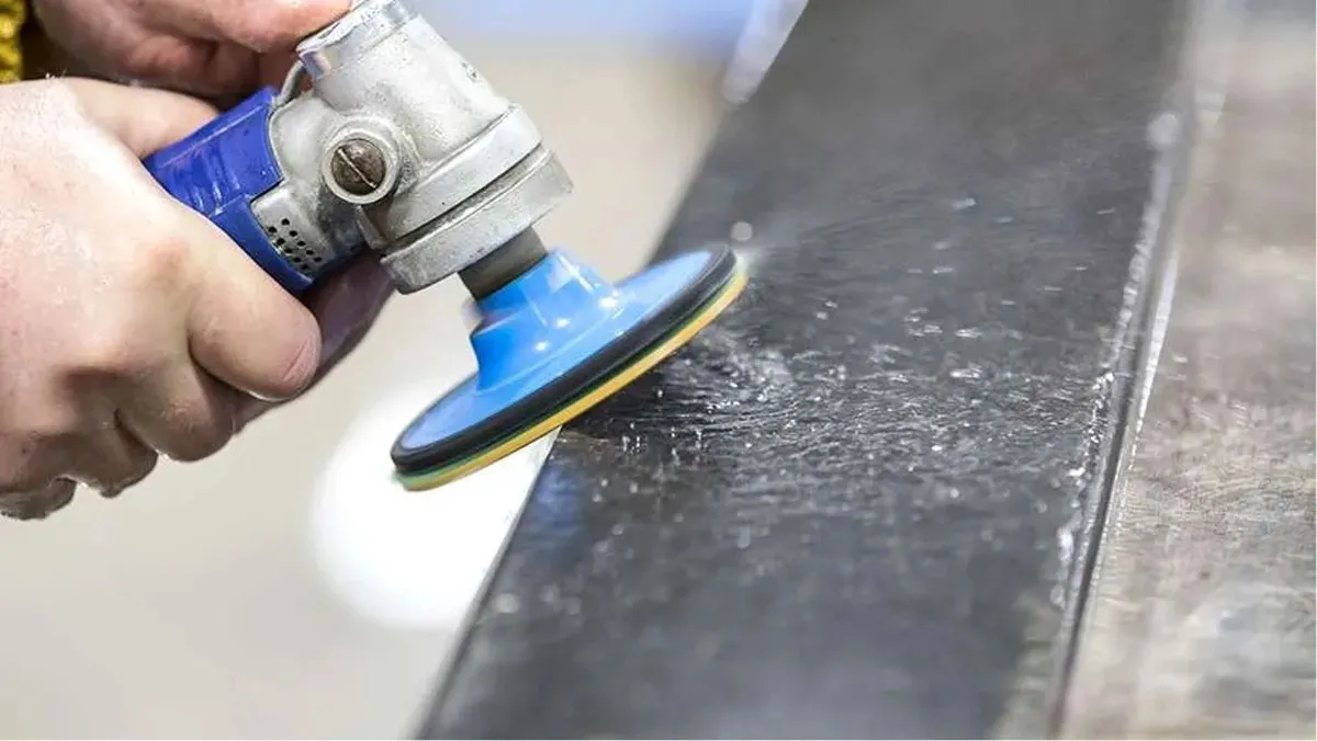 Handheld polisher smoothing a metal surface.