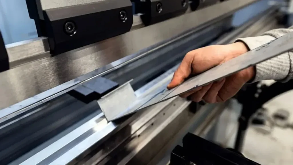 Worker operating a press brake machine.