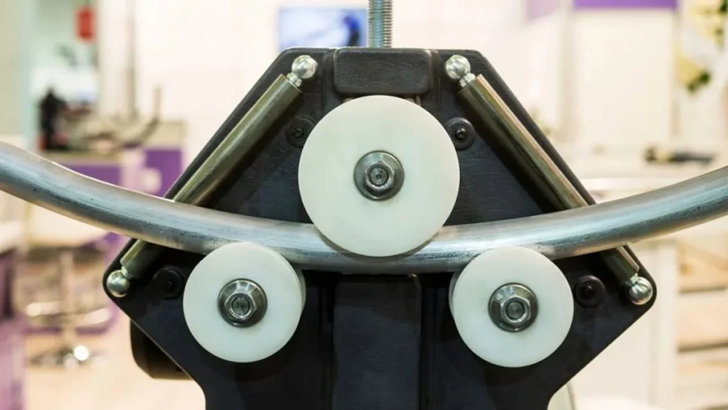 Metal pipe being shaped by rollers.