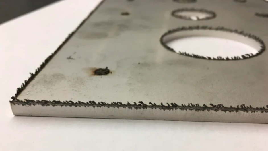 Metal plate with burrs on upper edge and around a hole