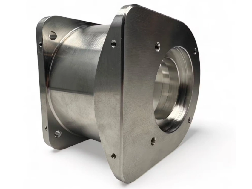 CNC-machined metal part with a cylindrical body and flanged ends featuring complex geometry and multiple holes