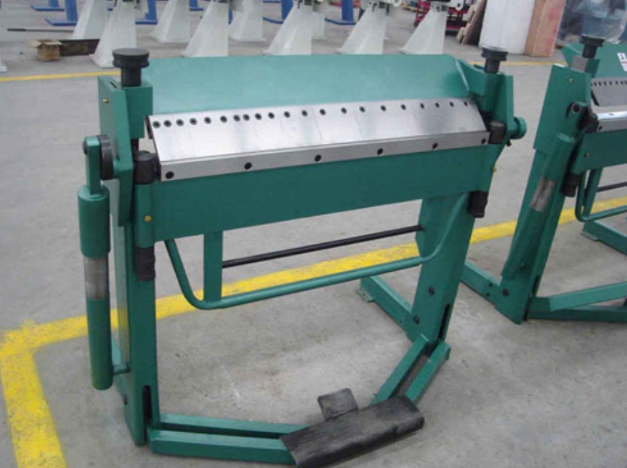 Green manual press brake bending silver sheet metal with a black foot pedal at the bottom