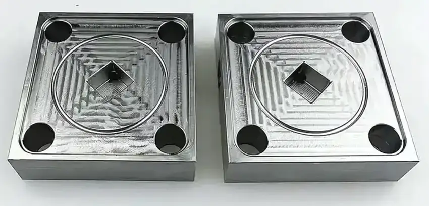 CNC machined titanium blocks with corner and center holes.