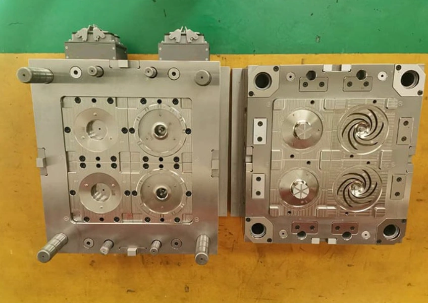 Multi-cavity injection molding tool showing machined steel mold halves with air release vents and other parts