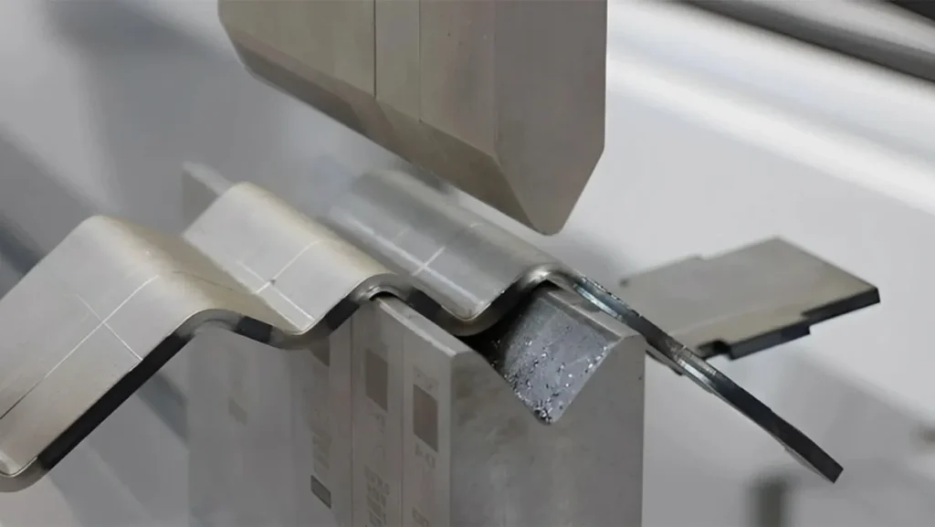Metal sheet being bent by an industrial press.