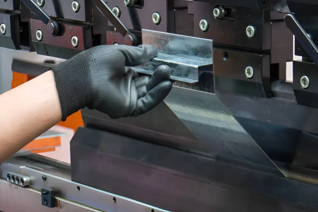 Operator performing sheet metal fabrication in an industrial setting, working with machinery and metal components.