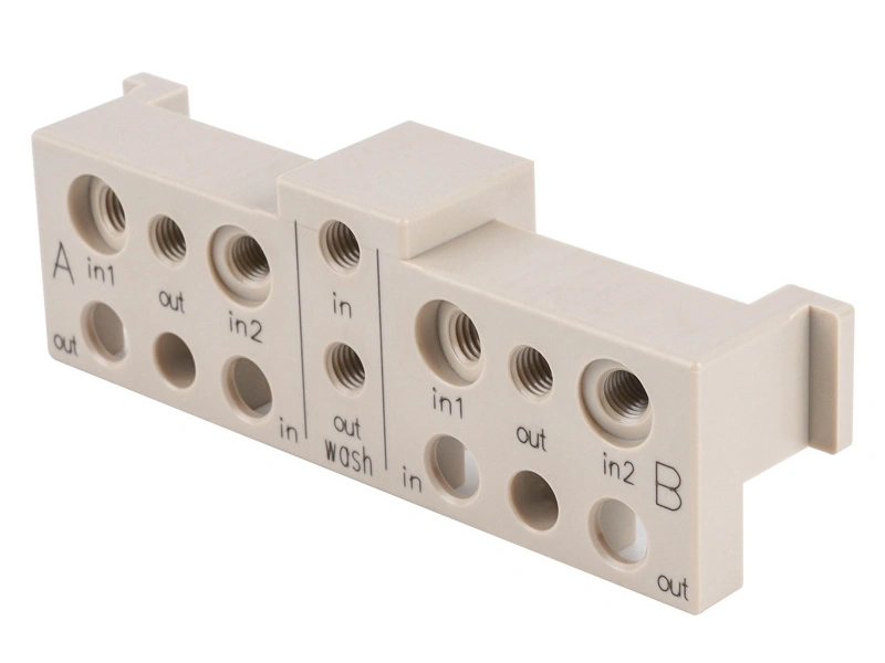 CNC-machined white plastic electronic connector block with threaded holes and labeled ports