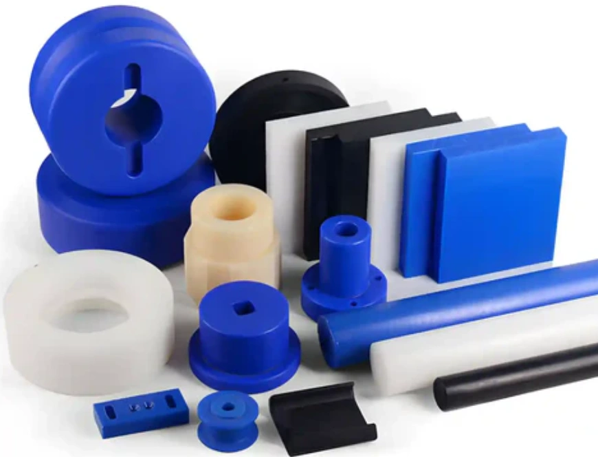 Collection of CNC-machined nylon parts in blue, black, and white, including blocks, rods, and custom components