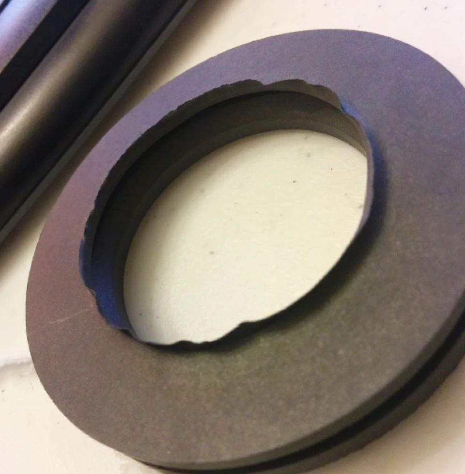 Machined plastic part showing burrs and rough edges on inner circular opening