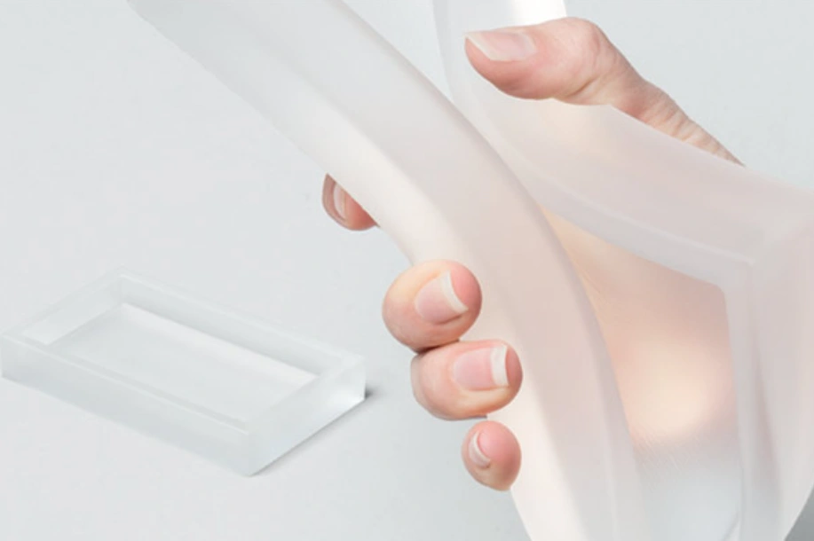 Hands bending a flexible soft polyurethane gel sheet, demonstrating material elasticity and softness