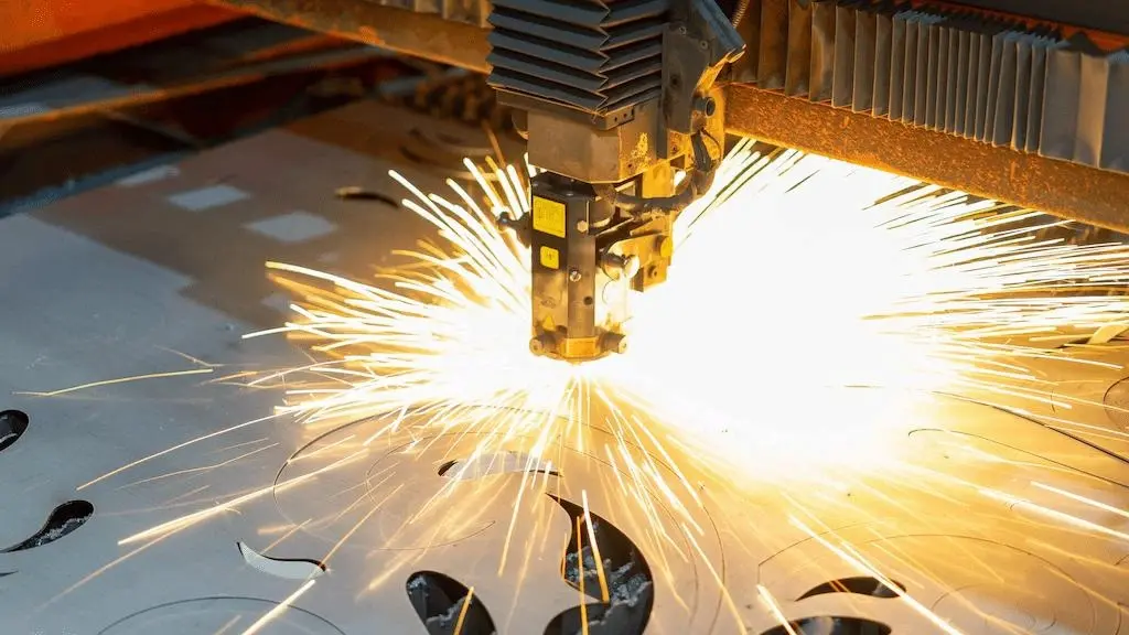 A close-up view of laser cutting a metal sheet with a scattering spark 