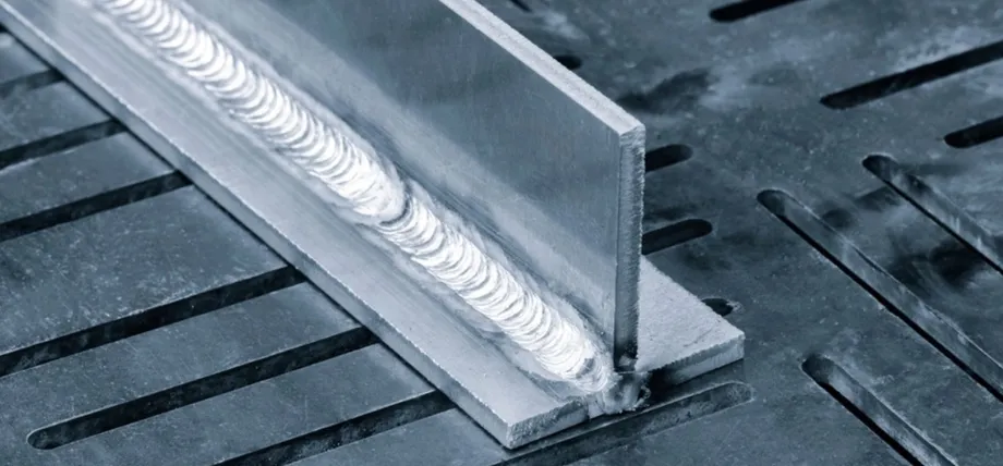 Close-up of a high-quality TIG weld bead with uniform, stacked dimes pattern along the corner joint of two stainless steel plates
