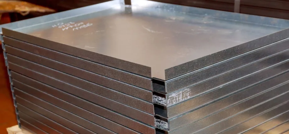 stacked pile of large, flat stainless steel or aluminum sheet metal plates with smooth, reflective surfaces and cleanly cut edges