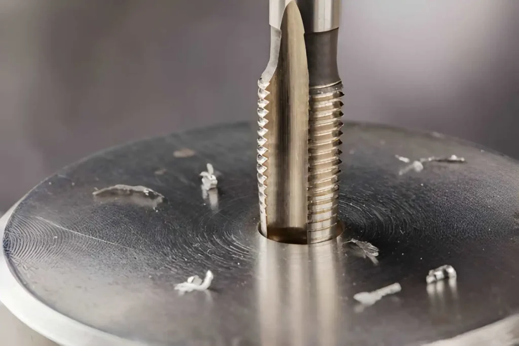 Drill bit performing a tap drill operation on a titanium part to prepare a threaded hole.