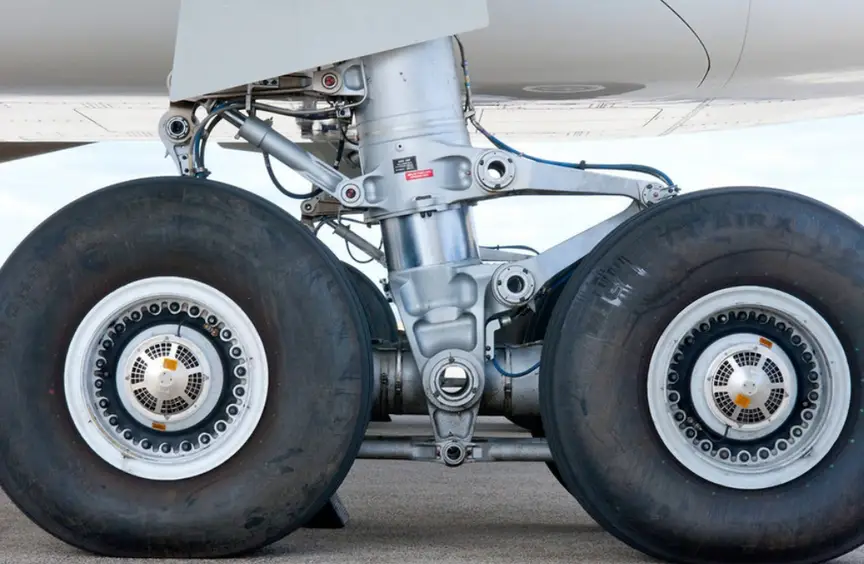 Close-up of a commercial aircraft main landing gear assembly with dual wheels and hydraulic strut