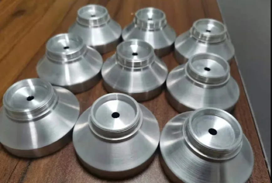 Small batch of identical turned aluminum cone-shaped components with center bores and threaded necks