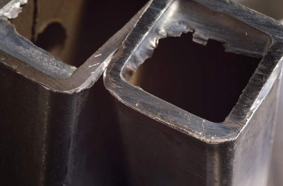 Close-up of burrs and rough edges on a poorly cut hollow metal square tube
