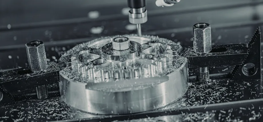 Close-up of a CNC milling machine precision-machining a large aluminum gear, with a cutting tool actively removing material and metal chips scattered