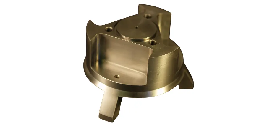 Intricate CNC-machined brass part featuring a central circular platform, curved open cavity, and multiple mounting holes