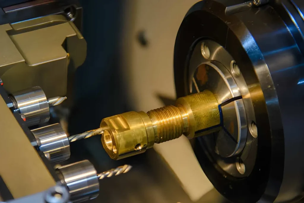 The image shows a Swiss CNC lathe drilling a hole in a brass coupling.