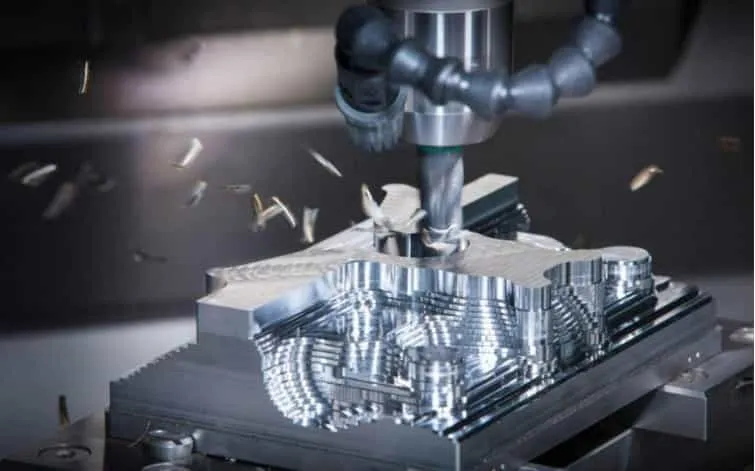 CNC milling machine cutting metal chips from a metallic workpiece during the subtractive manufacturing process