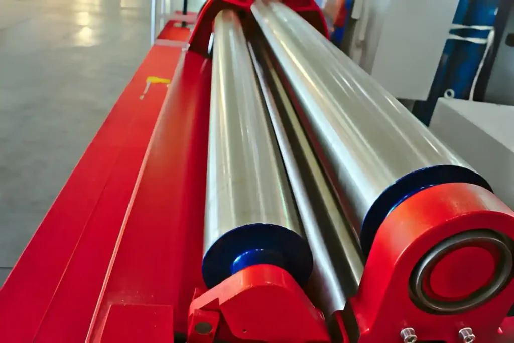 The image shows aluminum sheet metal being shaped using a roll-bending machine in a fabrication workshop.
