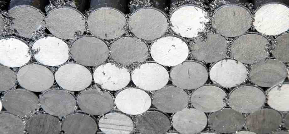 A cross-sectional view of stacked ferritic stainless steel round bars with visible metal shavings from cutting.