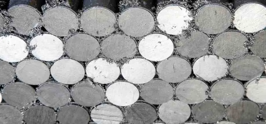 A cross-sectional view of stacked ferritic stainless steel round bars with visible metal shavings from cutting.