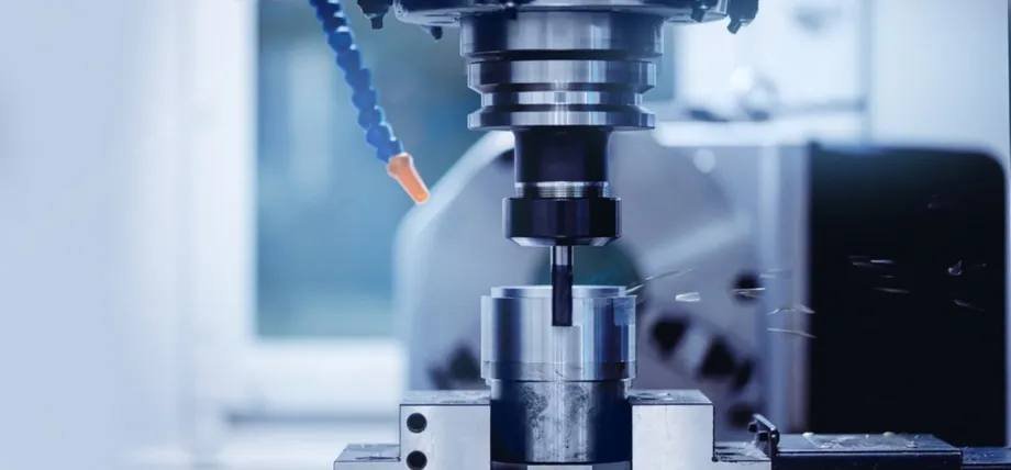A CNC milling machine actively cutting a Grade 303 stainless steel workpiece with visible metal chips flying.