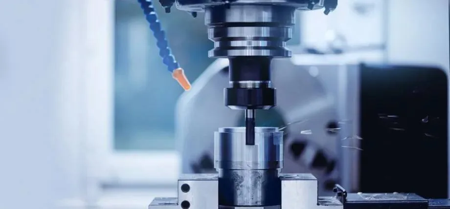 A CNC milling machine actively cutting a Grade 303 stainless steel workpiece with visible metal chips flying.