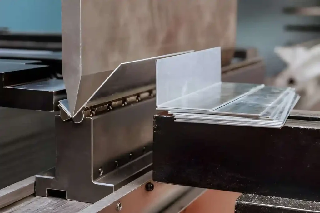 The image shows aluminum sheet metal being formed on a hydraulic press brake machine in a factory setting.