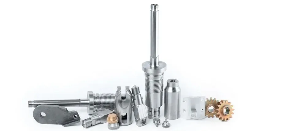 A collection of specialized martensitic stainless steel parts, including long threaded shafts, gears, and bushings.