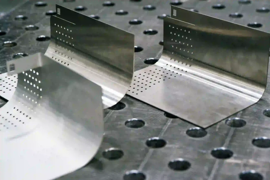 Precision-bent and perforated stainless steel sheet metal parts on the work surface