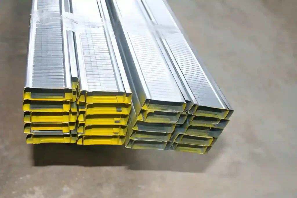 The image shows aluminum rectangular hollow tubes stacked on a concrete floor.