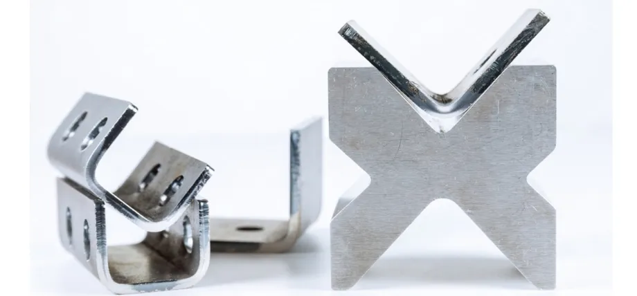 Precision-formed aluminum brackets, including U-shaped channels with holes and a large V-shaped angle bracket, displayed on a white background.