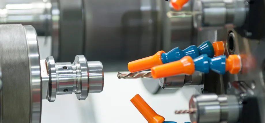 CNC lathe setup showing a rotating workpiece held in a chuck with multiple color-coded cutting tools positioned close to the machined part