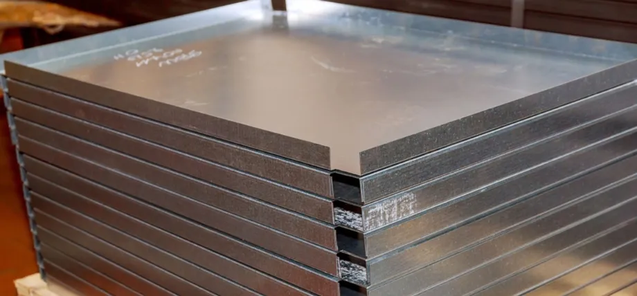 A stack of flat, silver aluminum sheet metal panels with smooth surfaces and visible edge markings